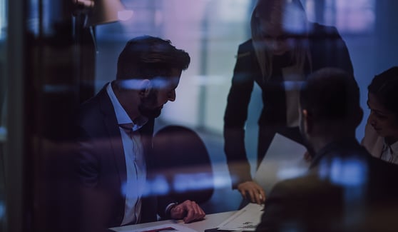 People discussing documents behind a glass wall