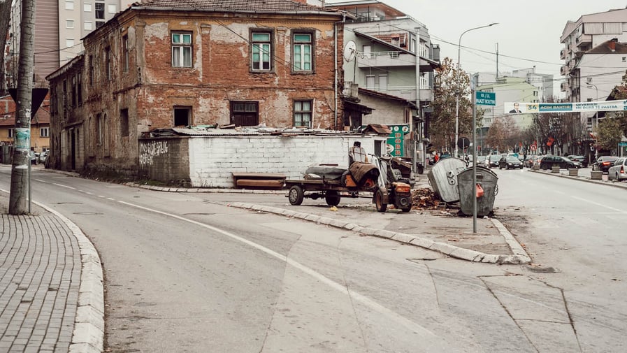 A street with a cart and a dilapidated brick building