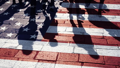 Painted US flag on the tar road with people crossing.