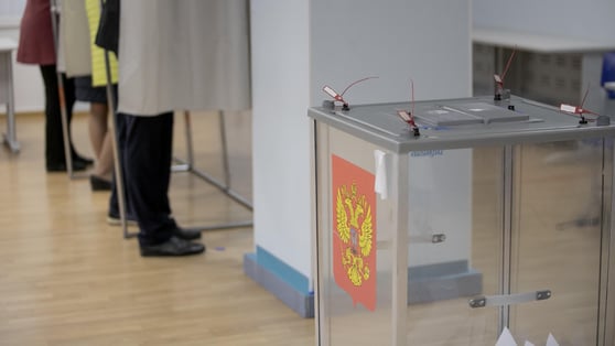 Ballot boxes for elections with the emblem of Russia at a polling station.