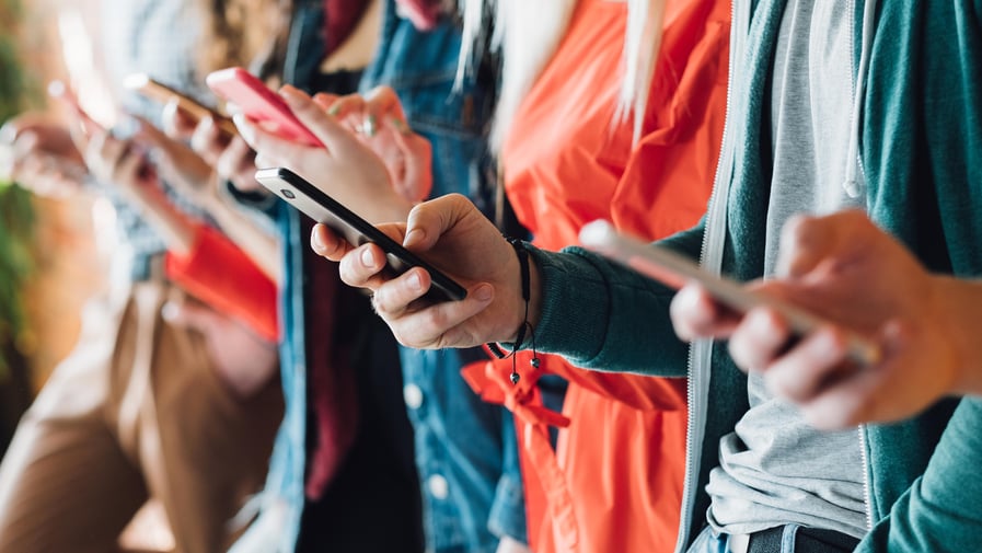 Colourful cropped closeup of people holding smartphones. 